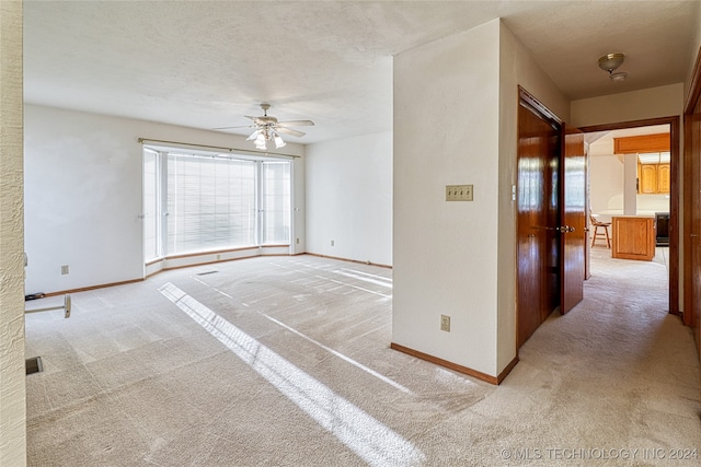 carpeted empty room featuring ceiling fan and a textured ceiling