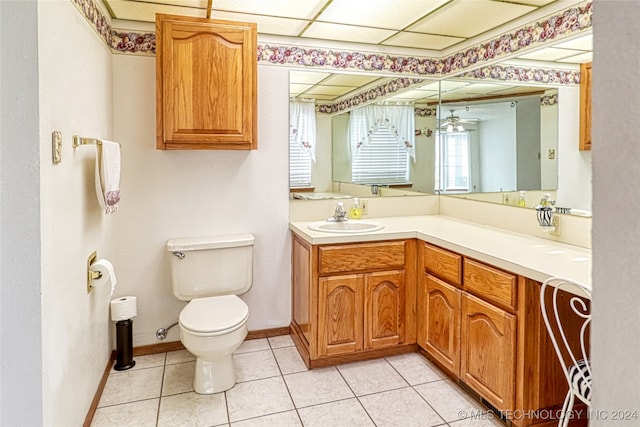 bathroom featuring vanity, a drop ceiling, toilet, and tile patterned floors