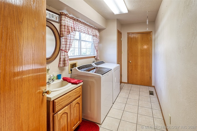 laundry room with cabinets, a textured ceiling, light tile patterned flooring, sink, and washer and clothes dryer