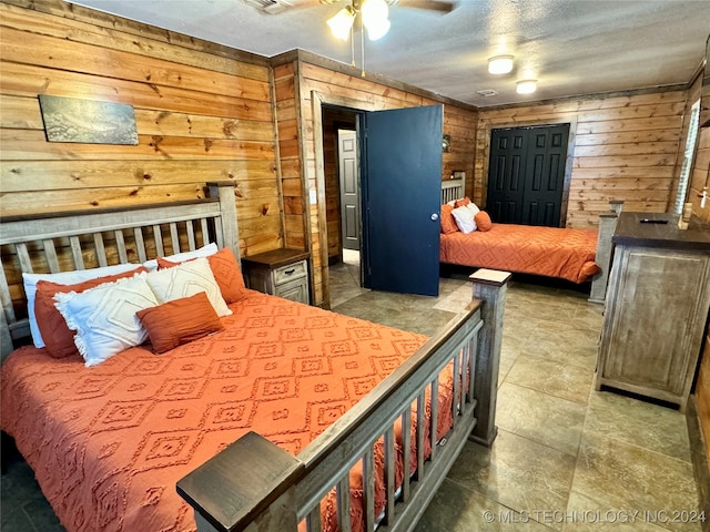 tiled bedroom featuring ceiling fan and wooden walls