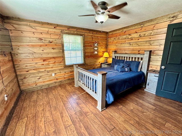 unfurnished bedroom featuring hardwood / wood-style floors, wood walls, and ceiling fan