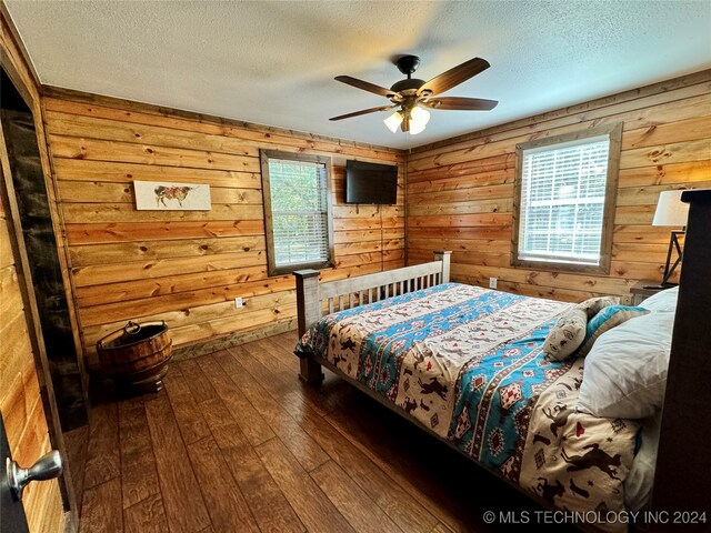 bedroom featuring wood walls, hardwood / wood-style floors, and multiple windows