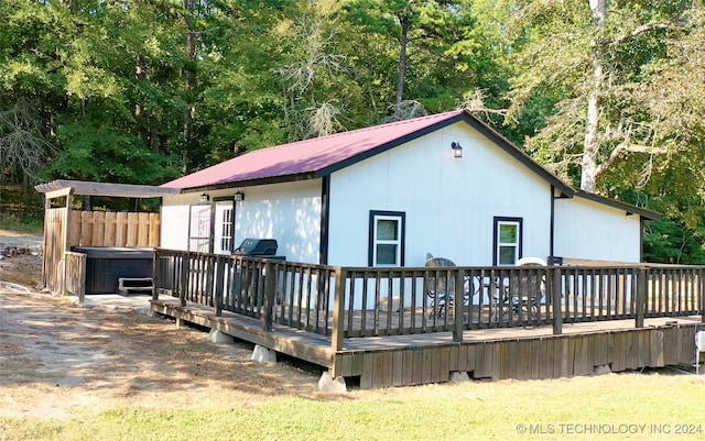 back of house featuring a wooden deck and a hot tub