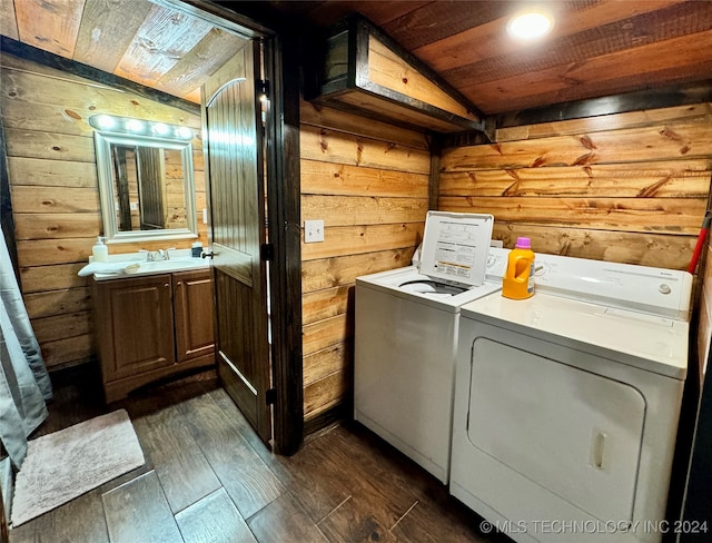 laundry room featuring dark wood-type flooring, wood ceiling, washer and dryer, sink, and wood walls