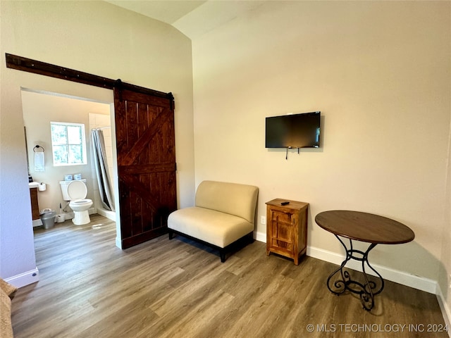 living area featuring hardwood / wood-style floors, a barn door, and vaulted ceiling