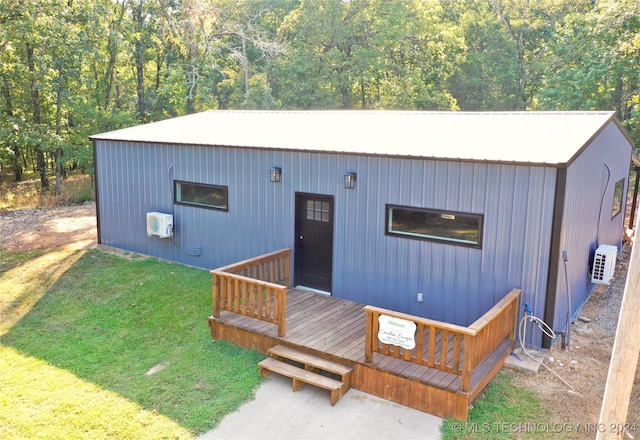 exterior space featuring a front lawn, a wooden deck, and a wall mounted air conditioner