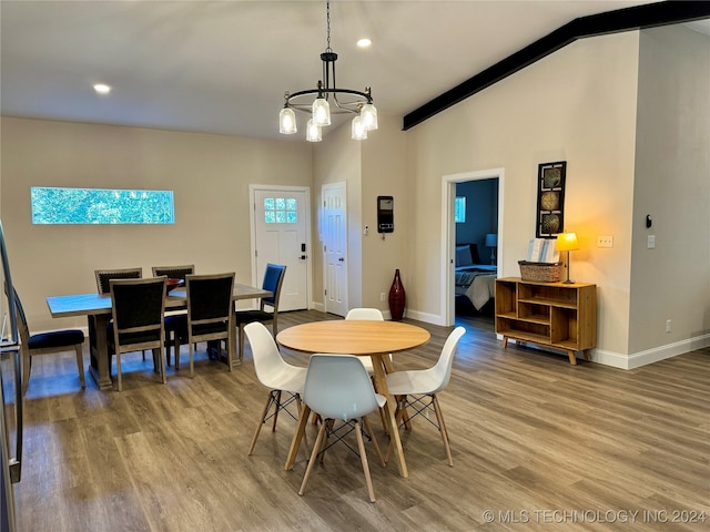 dining area with vaulted ceiling with beams, a notable chandelier, and hardwood / wood-style flooring