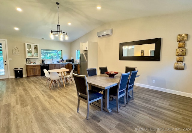 dining room featuring sink, a notable chandelier, vaulted ceiling, a wall mounted AC, and wood-type flooring