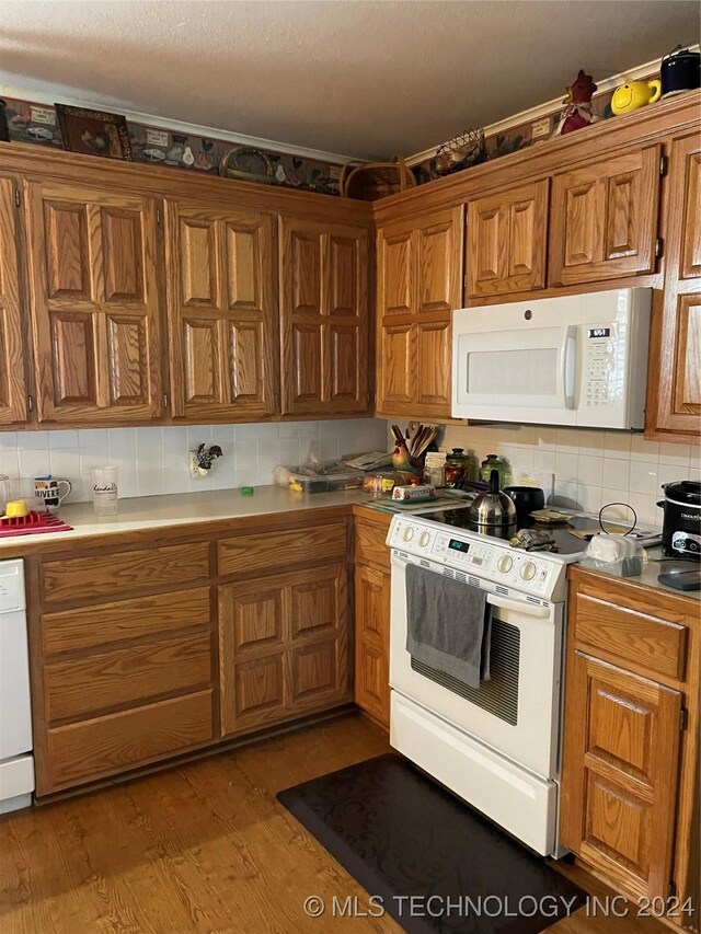 kitchen featuring backsplash, white appliances, and light hardwood / wood-style floors