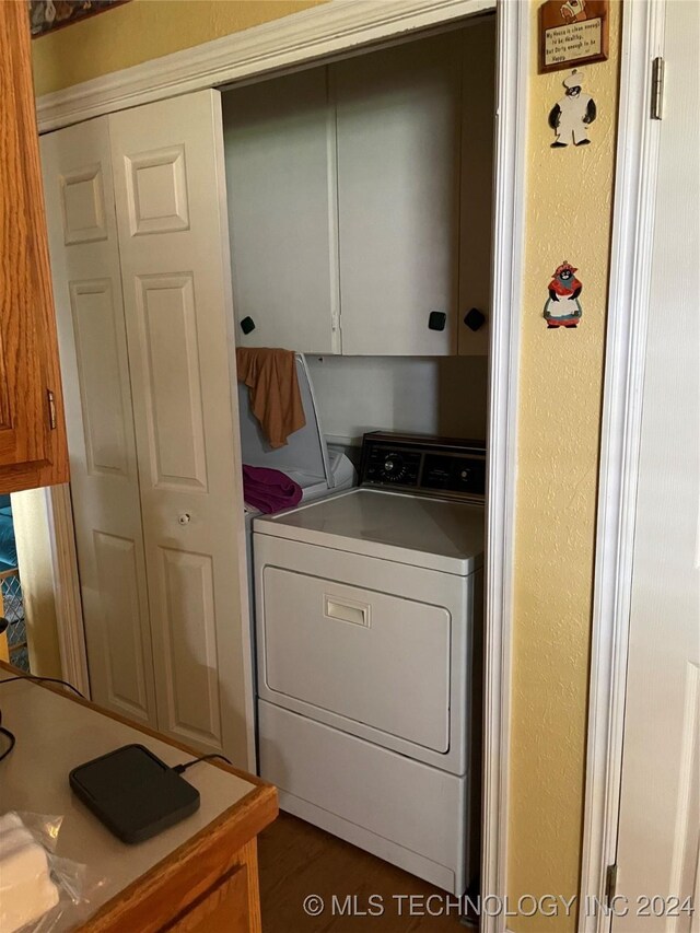 laundry area featuring dark wood-type flooring, independent washer and dryer, and cabinets