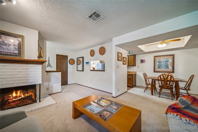 living room featuring light colored carpet, a fireplace, a textured ceiling, and ceiling fan