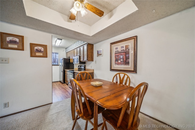 dining area featuring a textured ceiling, ceiling fan, and light carpet