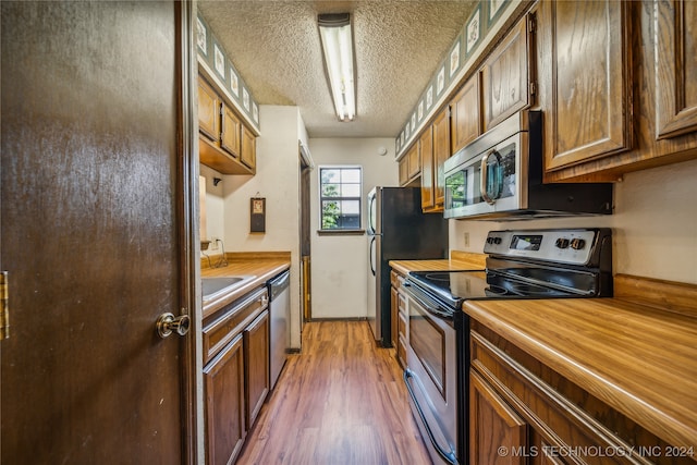 kitchen with appliances with stainless steel finishes, dark hardwood / wood-style flooring, and a textured ceiling