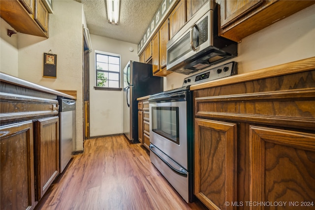 kitchen featuring a textured ceiling, hardwood / wood-style floors, and appliances with stainless steel finishes