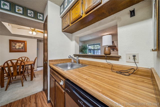 kitchen featuring a textured ceiling, dishwasher, sink, carpet flooring, and ceiling fan