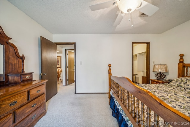 bedroom featuring a textured ceiling, light colored carpet, ceiling fan, and a closet