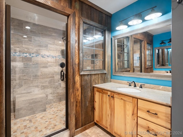 bathroom featuring vanity, a shower with shower door, and wooden walls