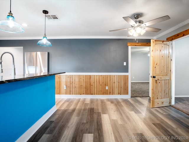 kitchen with pendant lighting, stainless steel fridge, wood-type flooring, and ornamental molding