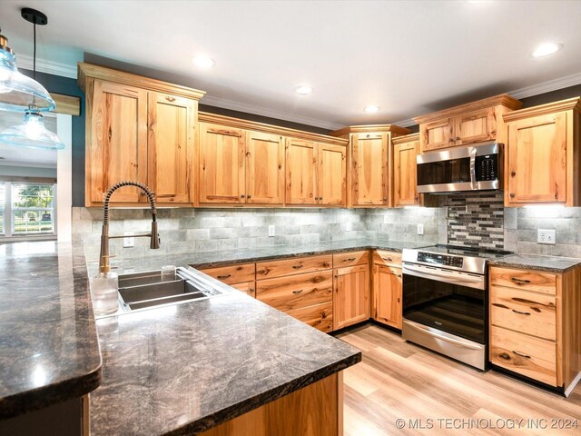 kitchen featuring appliances with stainless steel finishes, backsplash, crown molding, sink, and hanging light fixtures