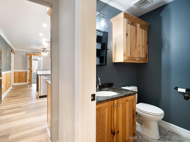 bathroom with ceiling fan, crown molding, wood-type flooring, toilet, and vanity