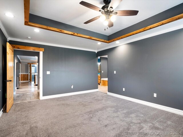 carpeted spare room featuring ceiling fan, a raised ceiling, and crown molding