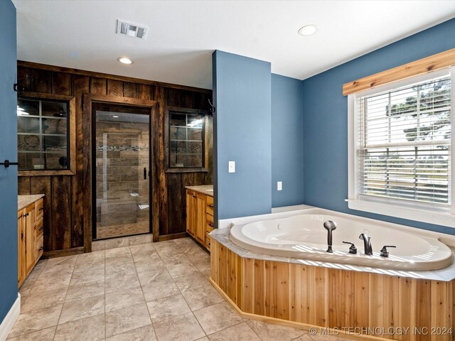 bathroom with tile patterned flooring, vanity, wood walls, and shower with separate bathtub