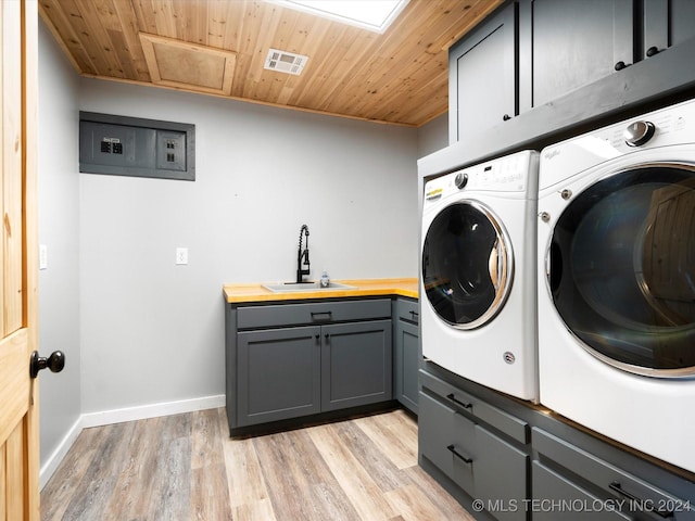 clothes washing area featuring washing machine and clothes dryer, sink, cabinets, light hardwood / wood-style flooring, and wood ceiling