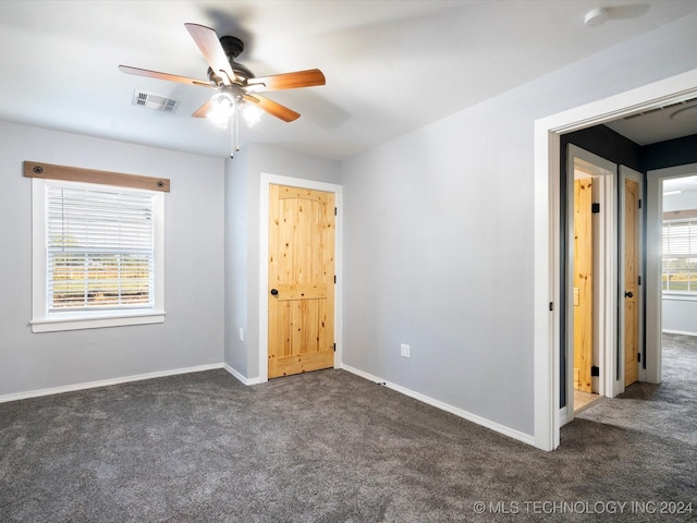 unfurnished bedroom featuring dark colored carpet and ceiling fan