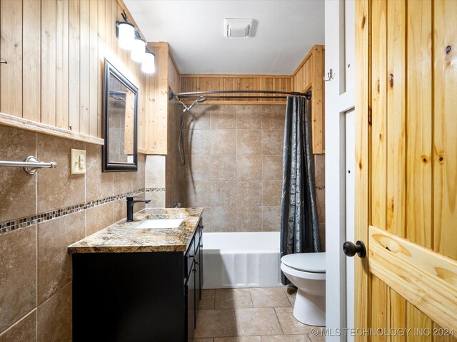 full bathroom featuring shower / bathtub combination with curtain, wooden walls, vanity, and toilet