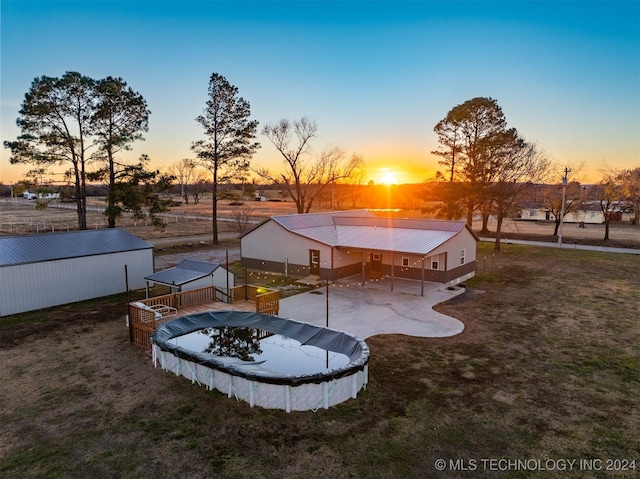 patio terrace at dusk with an outdoor structure and a covered pool