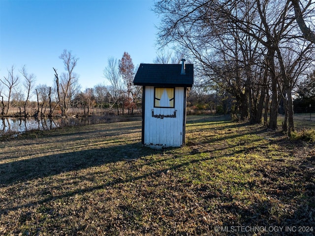 view of outdoor structure featuring a lawn and a water view