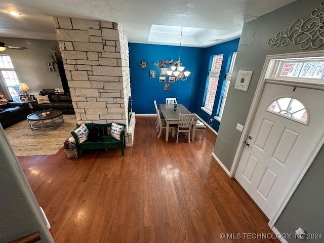 entryway with ceiling fan with notable chandelier, a tray ceiling, and wood-type flooring