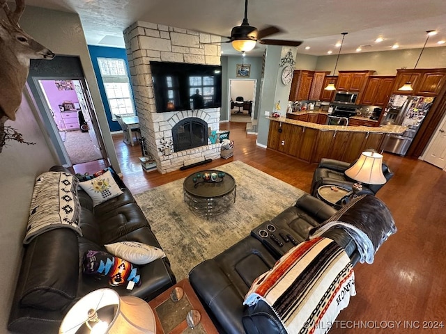 living room featuring ceiling fan, a fireplace, and dark hardwood / wood-style floors