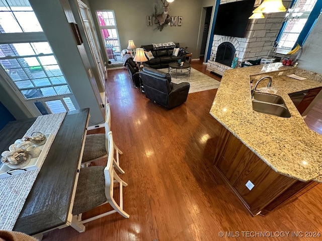 living room with sink, a stone fireplace, and hardwood / wood-style floors