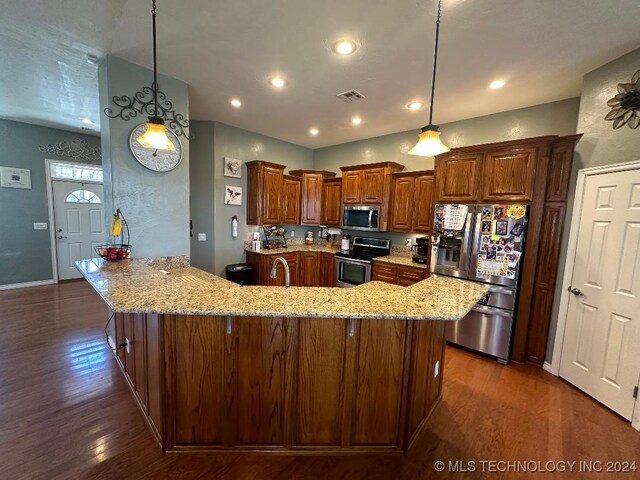 kitchen with appliances with stainless steel finishes, dark hardwood / wood-style floors, hanging light fixtures, and light stone countertops