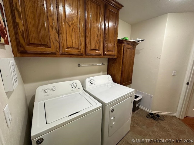 laundry room with separate washer and dryer, cabinets, and dark tile patterned floors