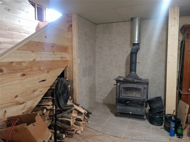 interior space with a wood stove and light tile patterned floors