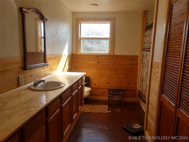 bathroom featuring vanity, wood walls, toilet, and hardwood / wood-style floors