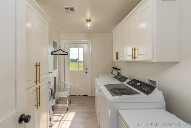 washroom with cabinets, washing machine and dryer, and light wood-type flooring