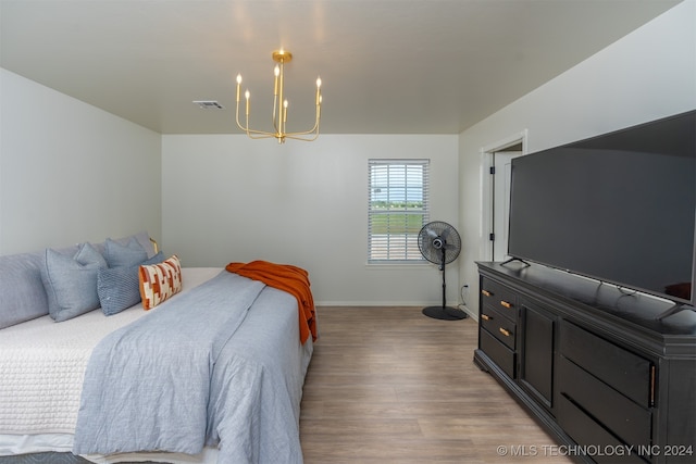 bedroom with an inviting chandelier and hardwood / wood-style flooring