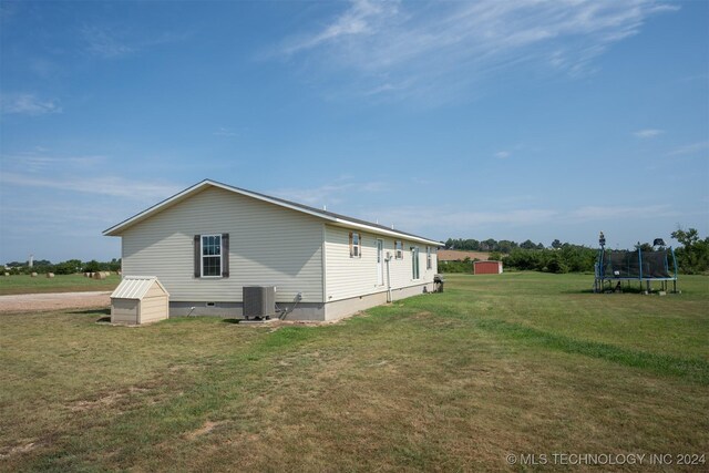 view of property exterior with an outbuilding, cooling unit, a trampoline, and a yard