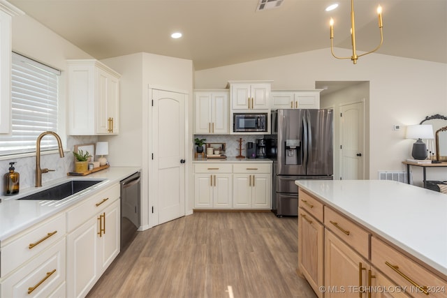 kitchen featuring stainless steel appliances, vaulted ceiling, sink, tasteful backsplash, and light hardwood / wood-style floors