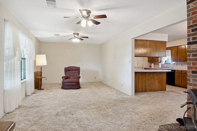 kitchen with black dishwasher, a textured ceiling, light carpet, ceiling fan, and kitchen peninsula