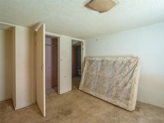 unfurnished bedroom with a textured ceiling and light carpet