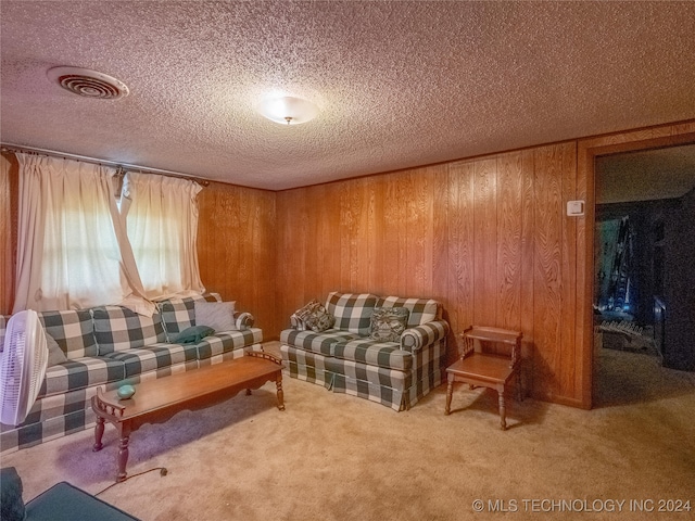 carpeted living room featuring wood walls and a textured ceiling