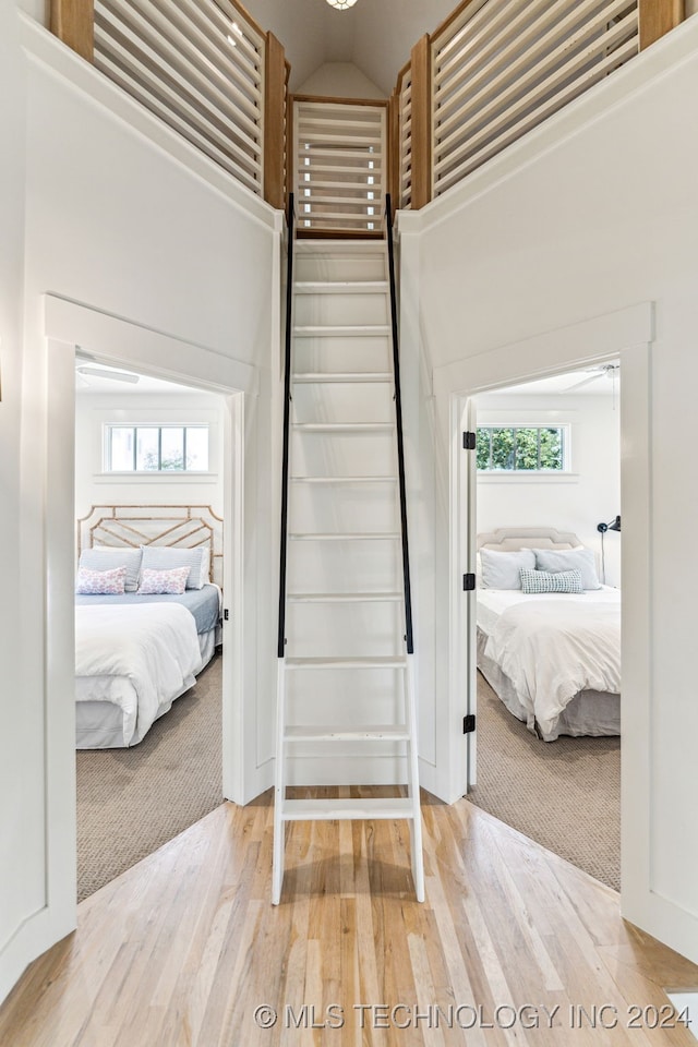 bedroom featuring a towering ceiling and light wood-type flooring