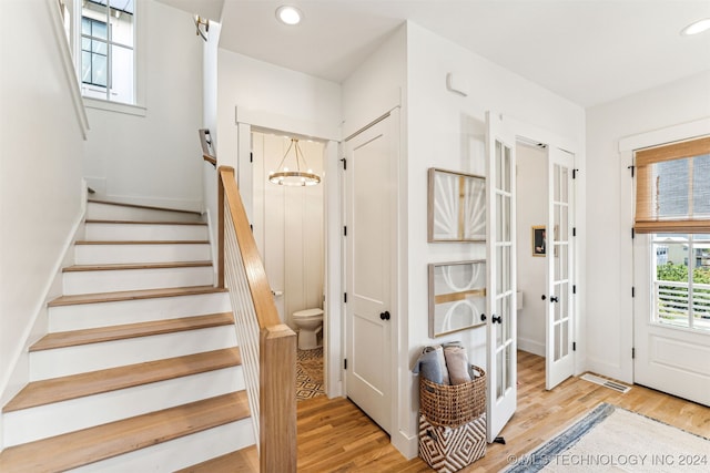 entryway featuring light hardwood / wood-style flooring, french doors, and an inviting chandelier