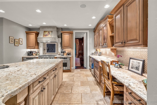 kitchen with custom range hood, tasteful backsplash, appliances with stainless steel finishes, light stone counters, and light tile patterned floors