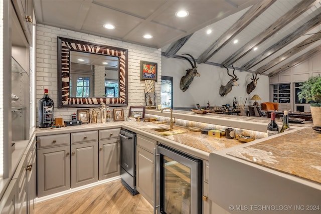 kitchen with light hardwood / wood-style floors, lofted ceiling with beams, brick wall, wine cooler, and gray cabinets