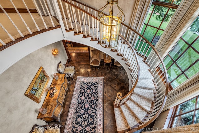 stairway with a towering ceiling and a chandelier